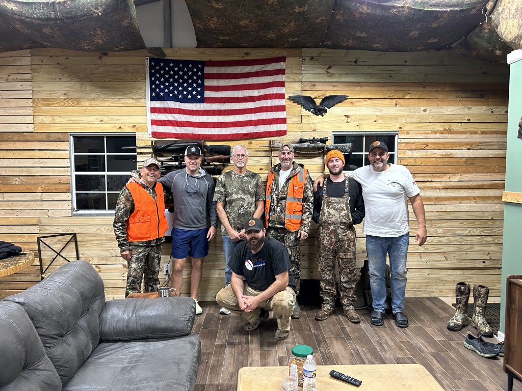 Redbillies-Outdoors-hunter picture inside the lodge with six hunters and ronny at the center.